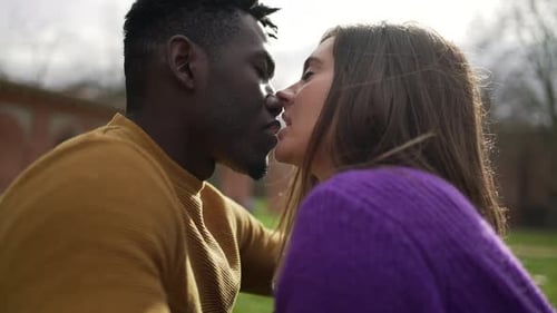 Young millennial couple kissing outside at park. intimate interracial kiss