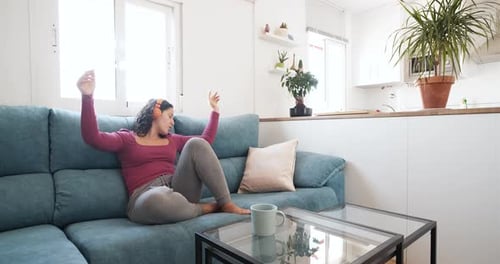 Woman Dancing Joyfully on a Couch at Home
