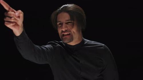 Man Gesturing and Speaking Against Black Background