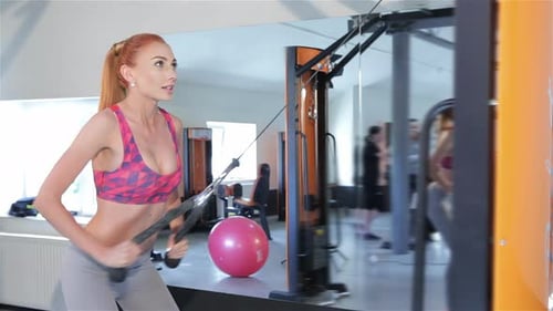 Woman Pulling the Rope of Gym Machine to Her Thighs at the Fitness Centre