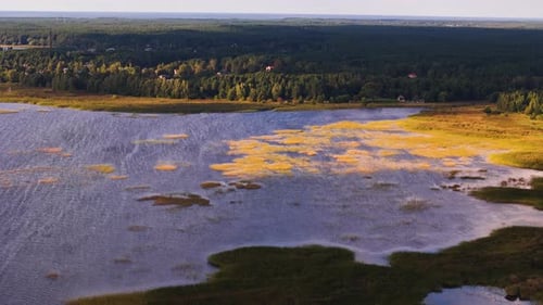 Aerial view of frozen ķīšezers lake in Latvian countryside landscape, forested area, skyline at suns
