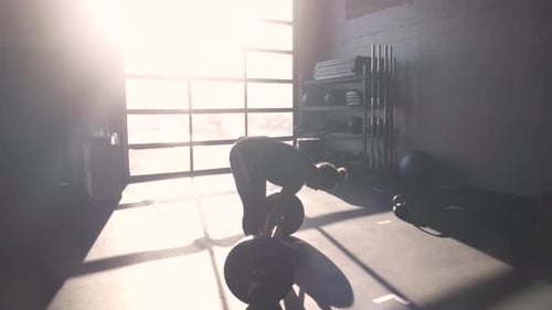 Dedicated young woman prepares for barbell squat at sunny cross training gym