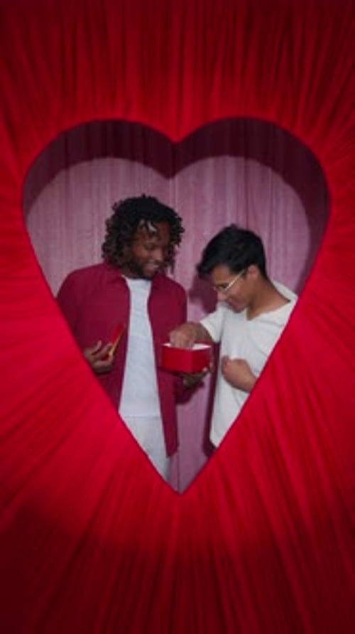 Male Couple Sharing Chocolates in Heart Valentine Photo Booth