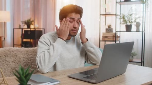 Young Man Types on Laptop at Home at Desk