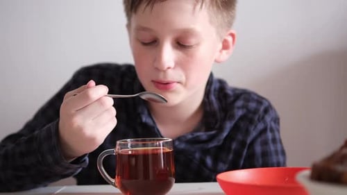 Boy stirs sugar into tea and tastes it