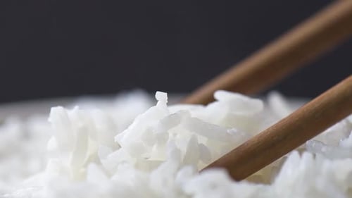 Palitos de madera que toman una pizca de arroz aromático caliente. Tiro macro
