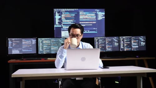 Man Working at Laptop with Multiple Monitors