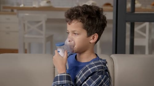 Sick Teenage Black Boy Treating Difficulties in Breathing with Asthma Inhaler