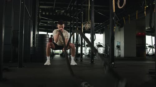 Professional Sportsman Bodybuilder Powerful Caucasian Man Exercise Battle Ropes Waves in Sport Gym