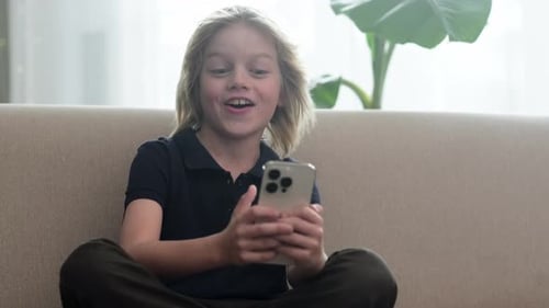 Blond Boy Chatting on Phone at Home
