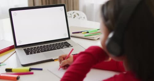 Girl Writing at Desk with Laptop