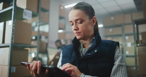 Female Inventory Manager Uses Tablet Computer in Warehouse Facility