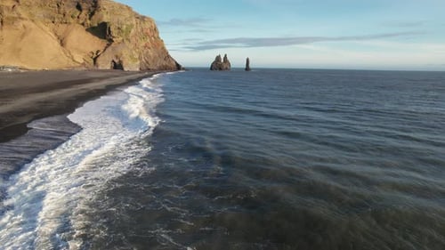 Waves Crashing On Shore Of Black Sand Beach In Iceland Southern Coast With Jagged Rock Formations In