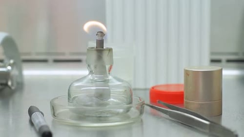 Candle flame burns in laboratory beaker illuminating clinical research equipment