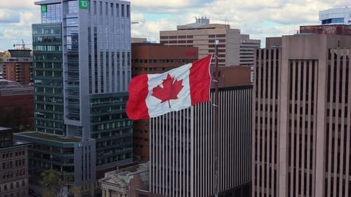 Aerial shot of Canadian flag waving among city buildings