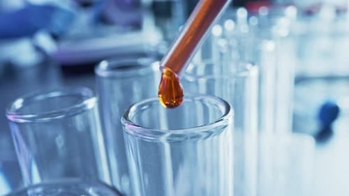 Amber Liquid Being Poured in Test Tubes
