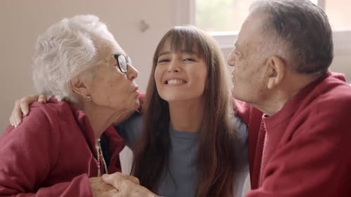 Affectionate Woman Embraced and Kissed by Senior Couple