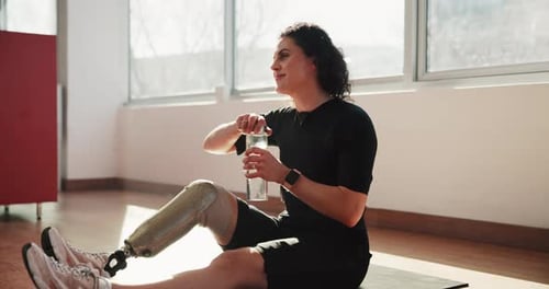 Fitness, woman and drinking water with prosthetic in gym from exercise, hydration