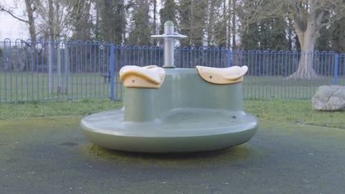 An empty children’s playground with a spinning carousel in slowmotion, in central London on a cold c