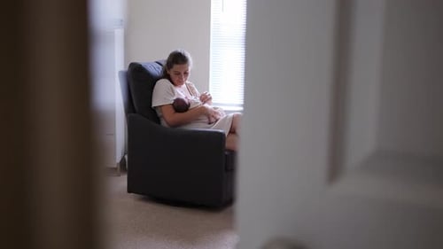 Woman Nursing Newborn Infant in Rocking Chair