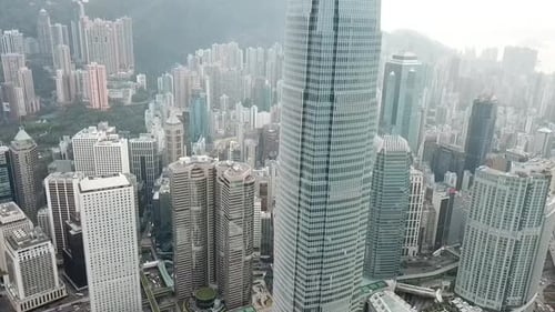 Aerial shot of a modern skyscraper in a coastal city against the sky, a drone rises above the citysc