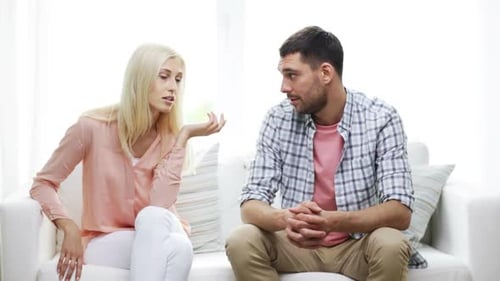 Woman and Man Seated on Couch Talking Together