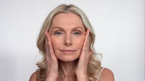 Mature woman applying facial cream for skincare routine