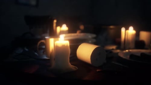 Flickering Candles on Dark Table with Melting Wax