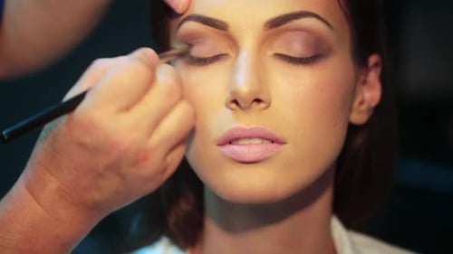 Woman receiving makeup with eyeshadow brush close up