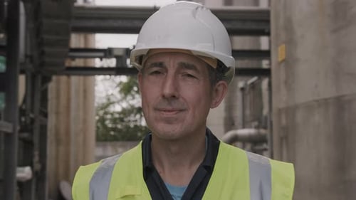 Man in Hard Hat and Vest at Industrial Site