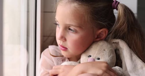 Child Hugging Stuffed Animal by Window
