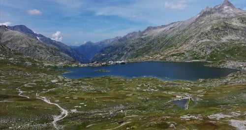 Totensee lake reflecting blue sky in swiss alps landscape. Pull Back Aerial Shot