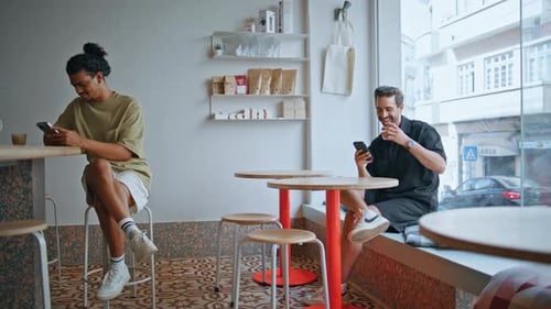 Two Guys Sitting Cafeteria Looking at Smartphone Cafe Visitors Relaxing Coffee