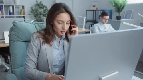 Close Up Face Young Businesswoman Speaks on Phone Working on Laptop Computer On Background People