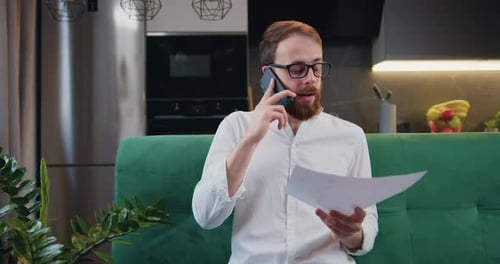 Man Talks on Phone and Reads Documents At Home