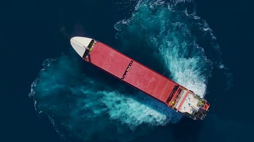 Aerial View Massive Cargo Ship Anchoring in the Vast Dark Blue Sea at Sunrise