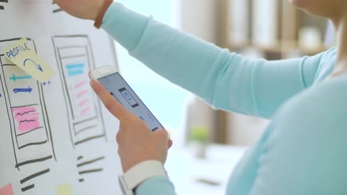 Woman Designs Mobile App Wireframe Using Smartphone