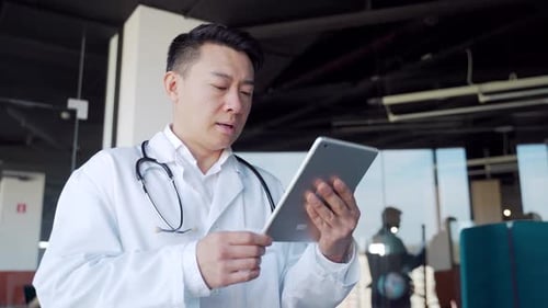Asian male doctor advise patient remotely using digital tablet. Communicates online talks on video