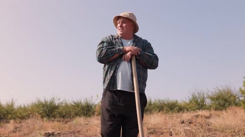 Adult Farmer Holds Shovel in Rural Field