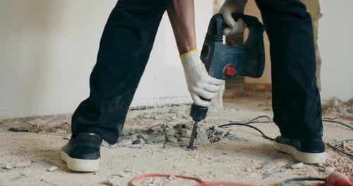 Worker Demolishing Concrete Floor with Jackhammer