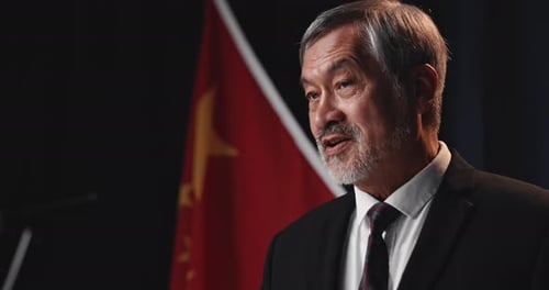 Man Speaks with Flag in Background Close Up