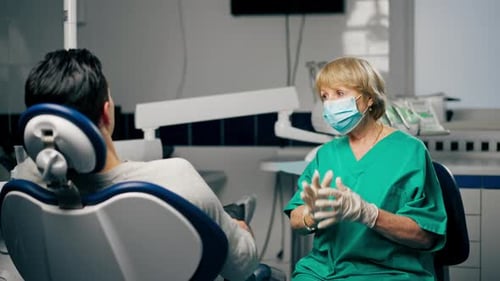 General Shot in a Dental Clinic Patient with a Female Dentist Adjusts a Mask on His Face