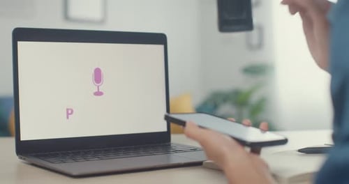 Person uses smartphone next to laptop podcast graphic