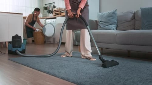 Person Vacuuming Carpet While Someone Does Laundry