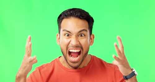 Face, green screen and man screaming, angry and upset guy against a studio background