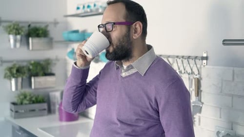 Junger Mann entspannt sich und trinkt Kaffee in der Küche zu Hause der 30er