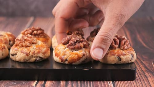 Cookies topped with walnuts on a black board