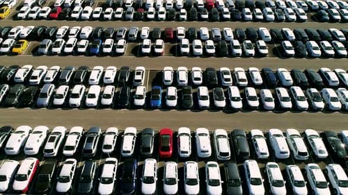 Aerial footage of finished cars ready to be shipped on huge distribution center