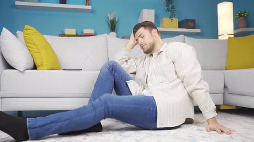 Depressed young man sitting on the floor in a sad state.