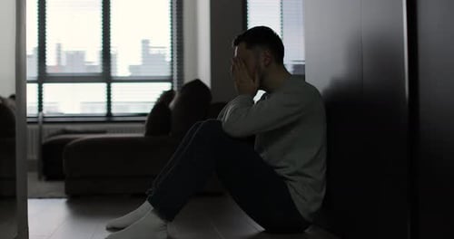 Sad Young Man Sitting on Floor in Apartment